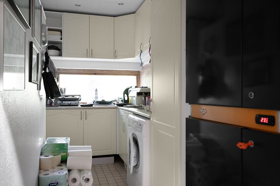 A compact and modern kitchen with laundry appliances, featuring white cabinets and natural light.