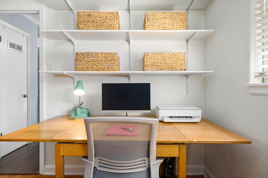 A clean, modern home office with a computer, shelves, and wicker baskets.