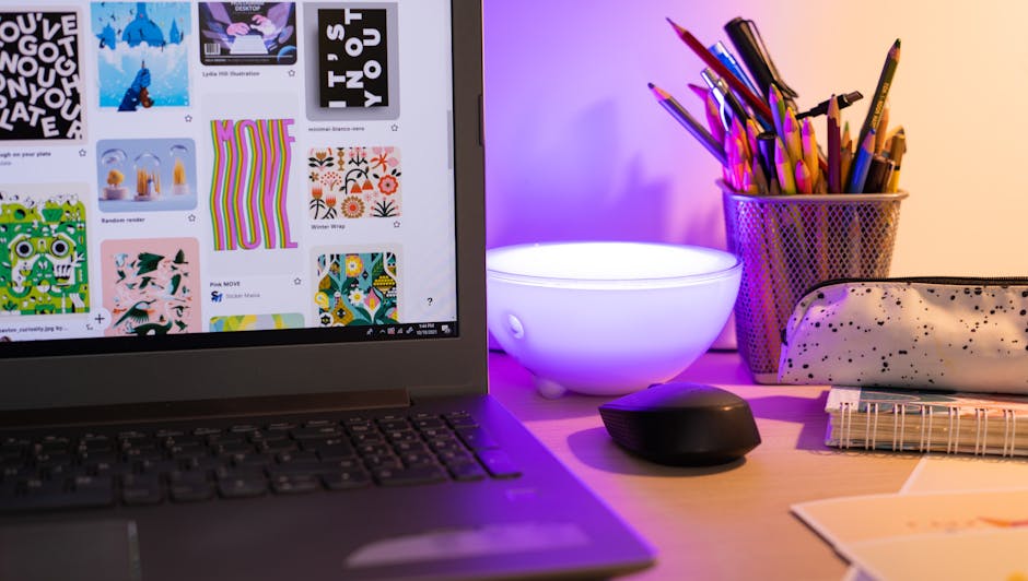 A colorful workspace featuring a laptop, art supplies, and decorative lighting.