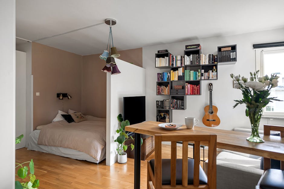 A stylish studio apartment with a cozy bed, bookshelf, and modern decor.
