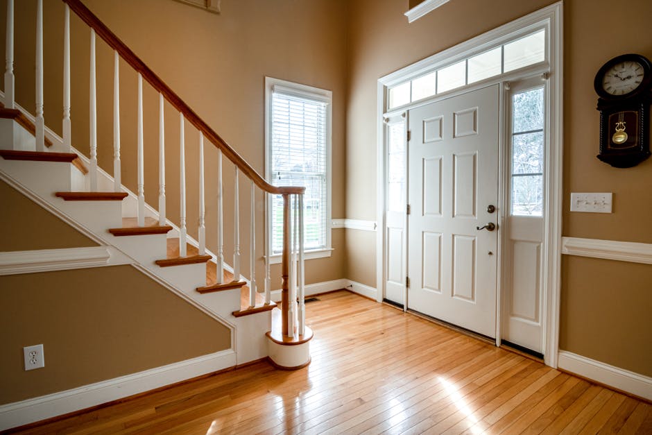 A bright and elegant entrance featuring a wooden staircase and classic interior design.