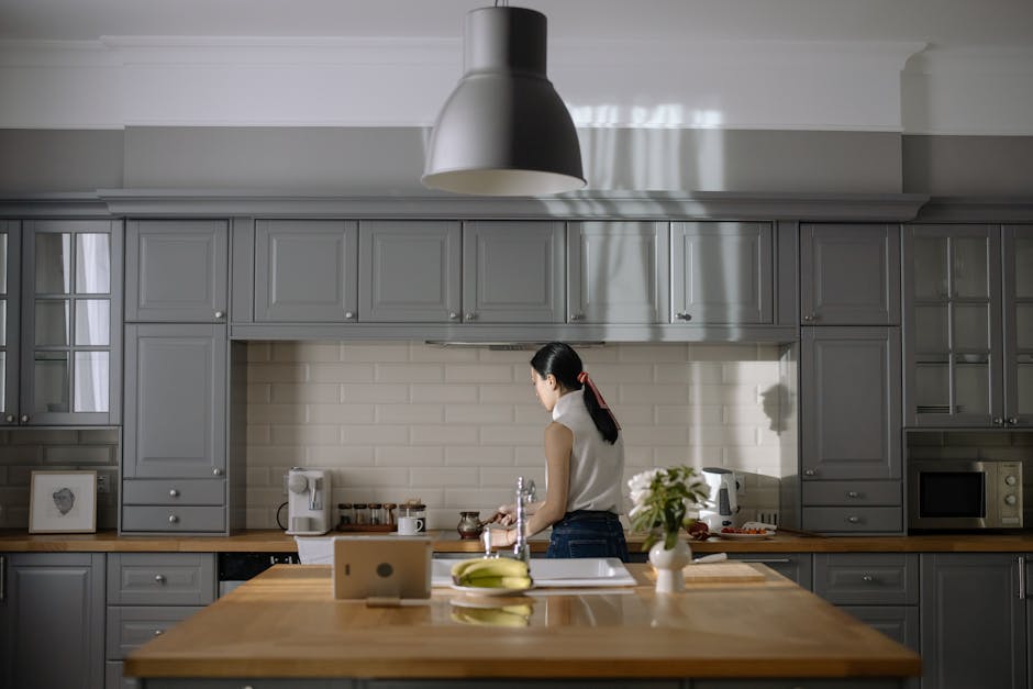 Woman cooking in a contemporary kitchen with gray cabinets and wooden countertops.