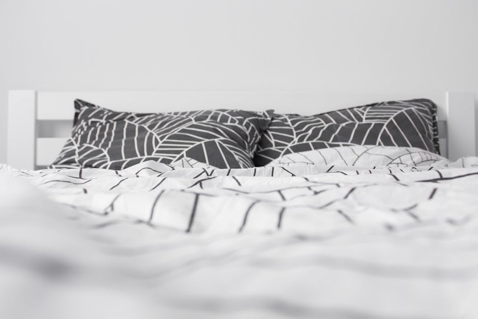 A stylish and modern black and white minimalist bedroom with geometric pattern bedding.