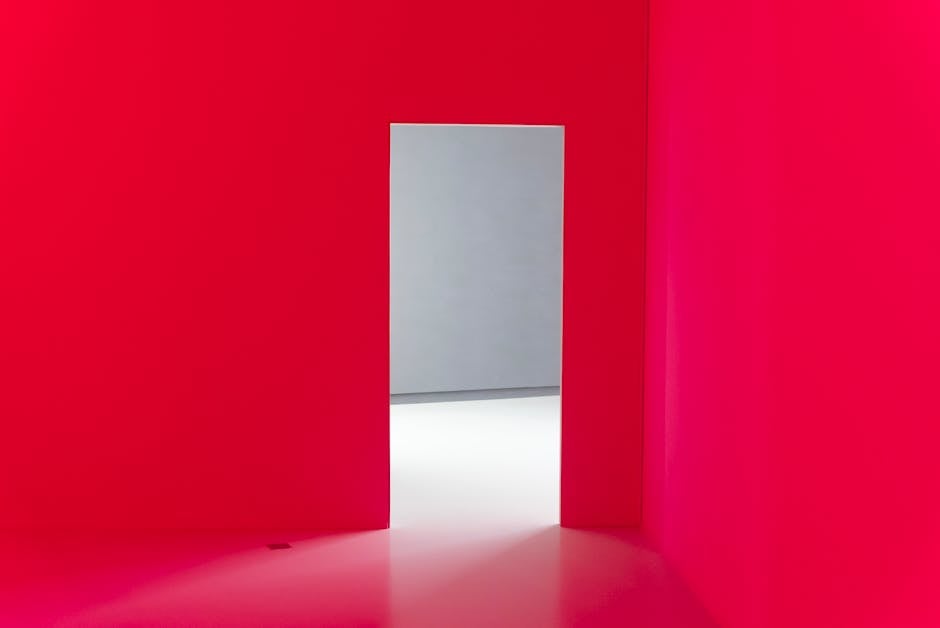Abstract interior with bright red walls and an open doorway leading to a minimalist white room.