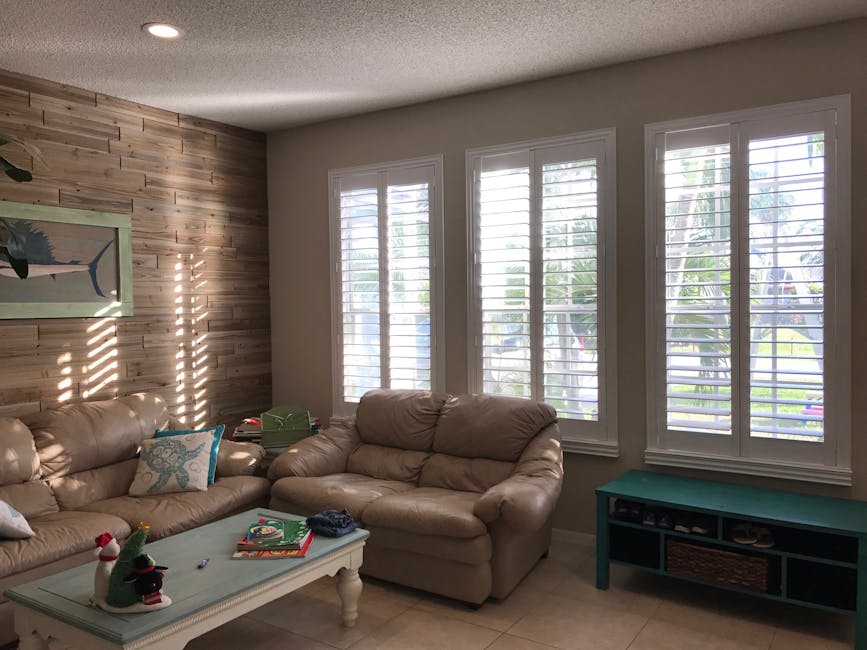 Bright minimalist living room with beige sofas and wooden paneling.