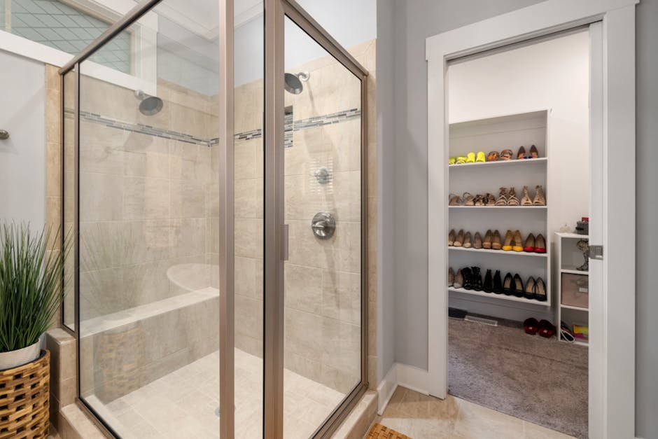 Spacious modern bathroom with glass shower and closet with organized shoe storage.