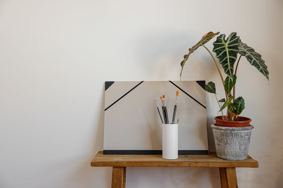 A minimalist workspace featuring art supplies on a wooden desk alongside a potted plant.