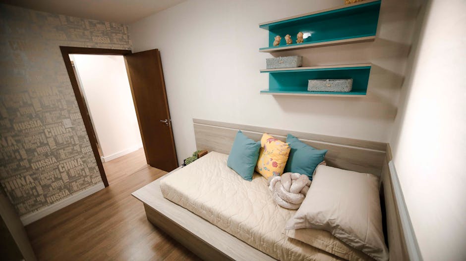 A well-lit modern bedroom featuring a comfortable daybed, colorful pillows, and decorative shelves.