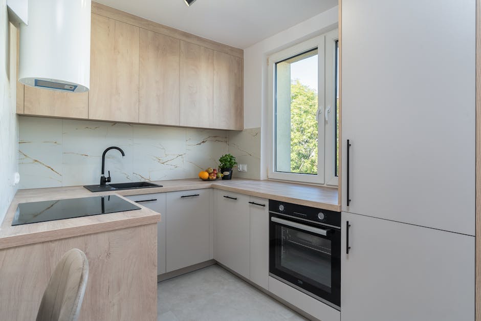 Bright minimalist kitchen with light wood cabinetry and modern appliances.