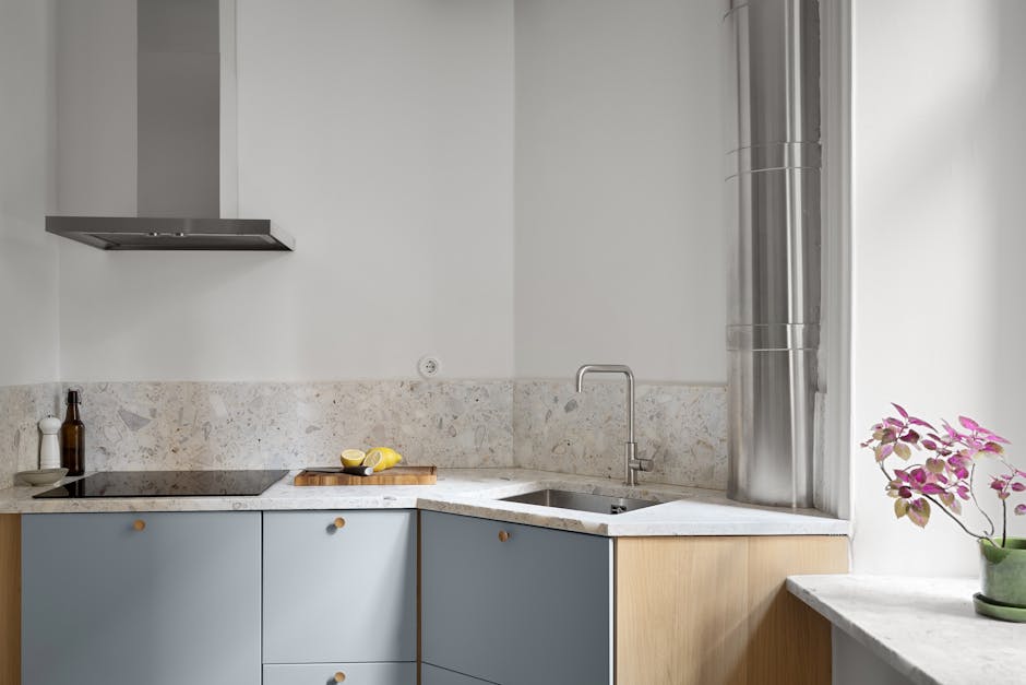 Elegant minimalist kitchen with blue cabinets, marble countertops, and stainless steel elements.