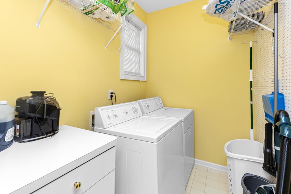 Spacious laundry room with washer, dryer, and shelves in bright setting.