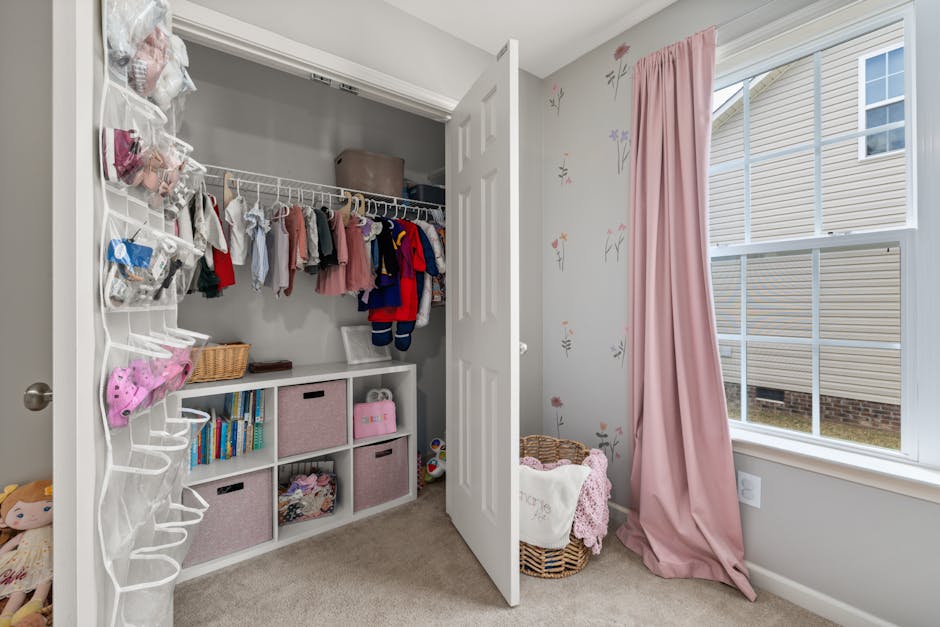 A neatly organized children's closet with clothes, toys, and pink decor in a bright room.