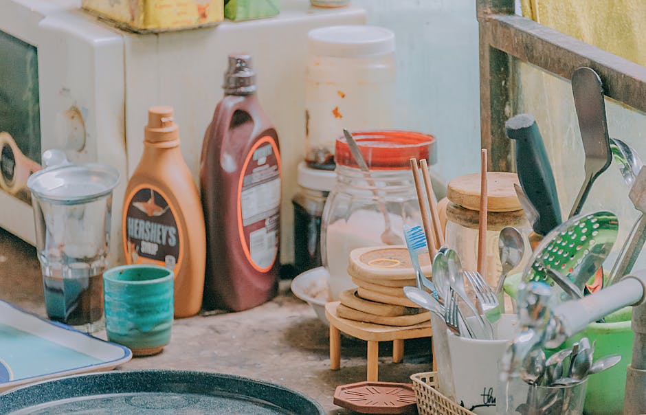 Close-up of a cluttered kitchen counter with utensils, jars, and a Hershey's syrup bottle.