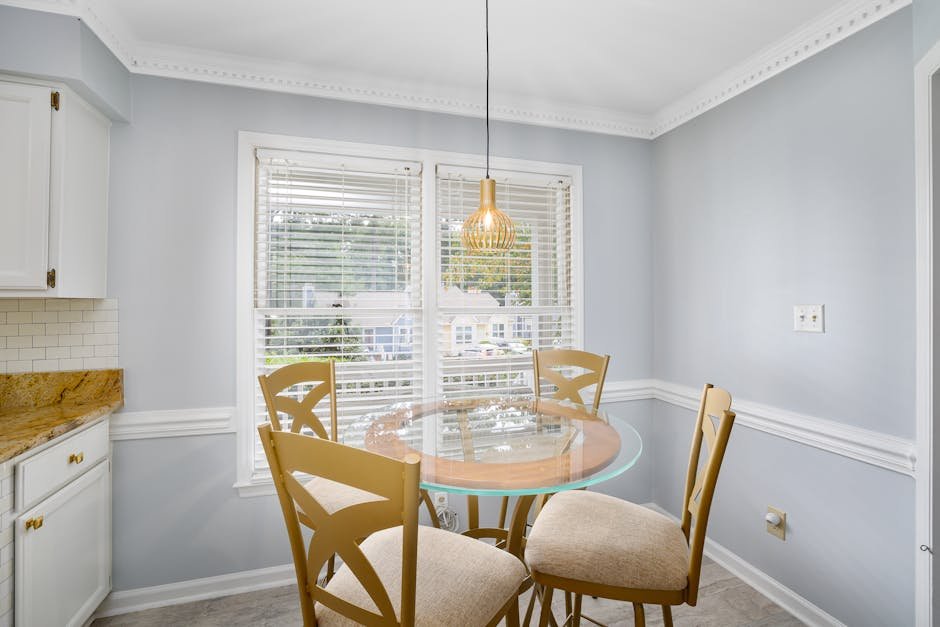 Bright and elegant dining room featuring a glass table and wooden chairs under a decorative ceiling lamp.