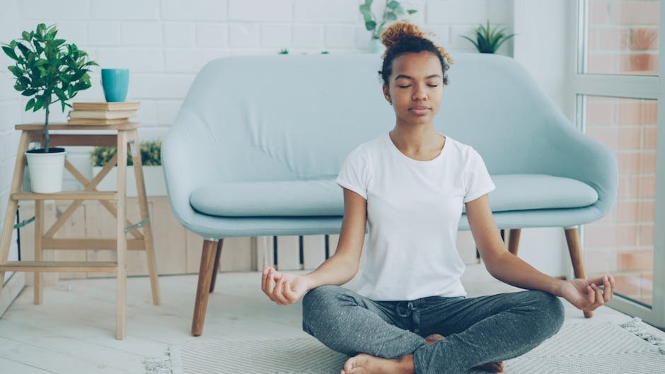 A woman meditates in a serene living room setting with modern decor.
