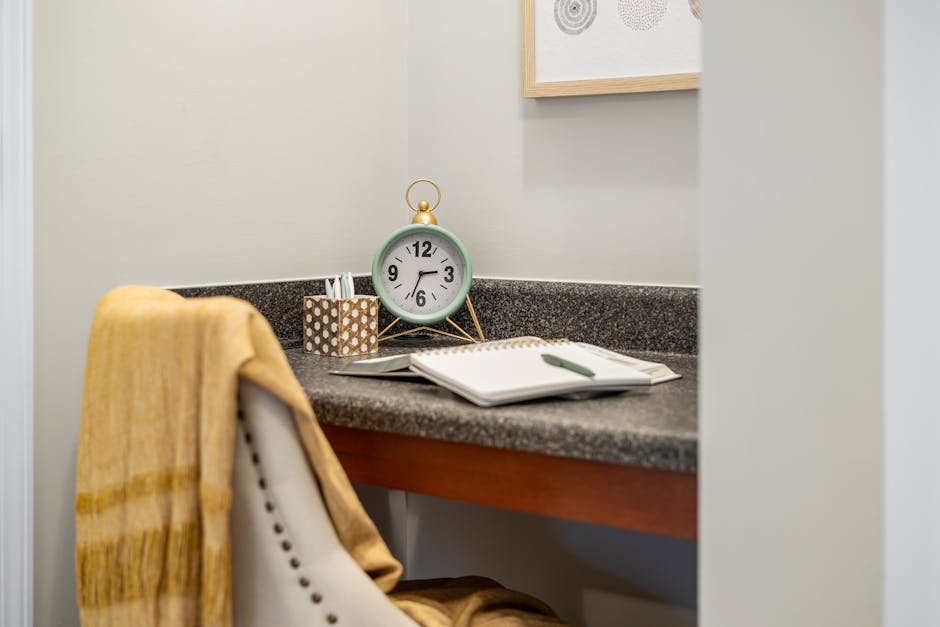 A cozy home office corner with a clock, notebook, and comfortable chair for productivity.