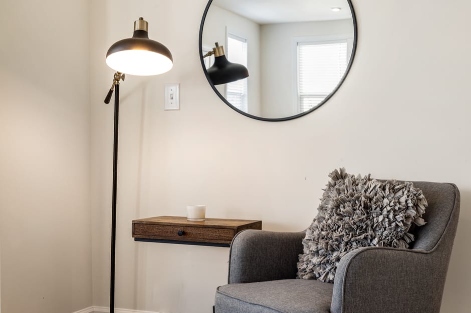 Comfortable corner with armchair, wooden shelf, and lamp in a modern living room.