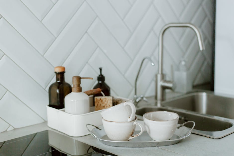 A simple and clean kitchen counter setup featuring tea cups and soap dispensers.