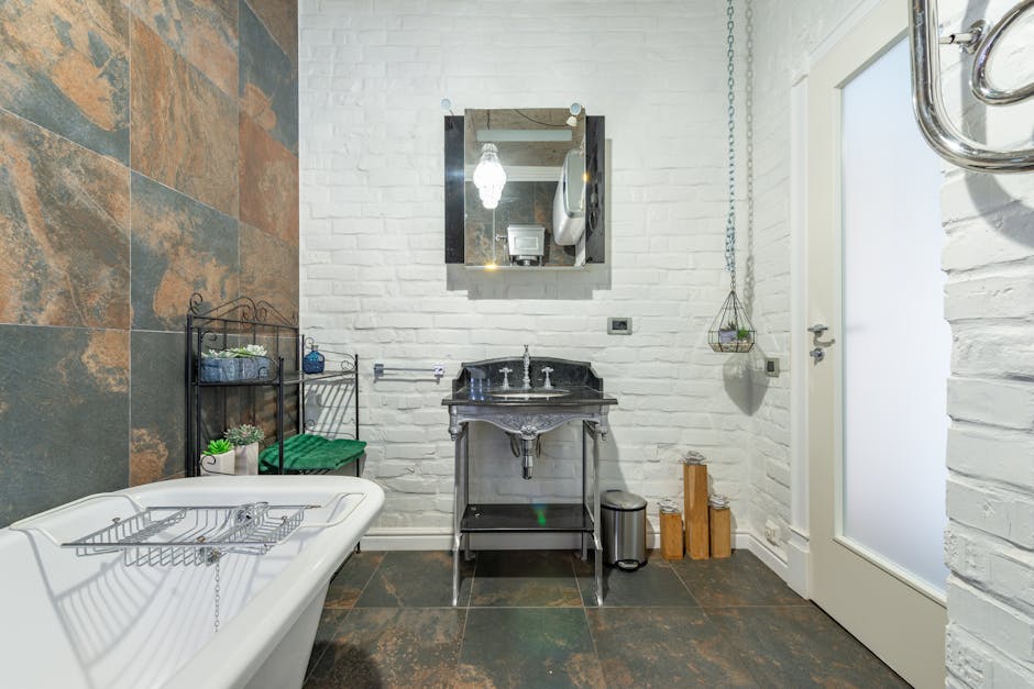 Elegant bathroom featuring a freestanding bathtub, rustic tiles, and modern fixtures for a chic interior design.