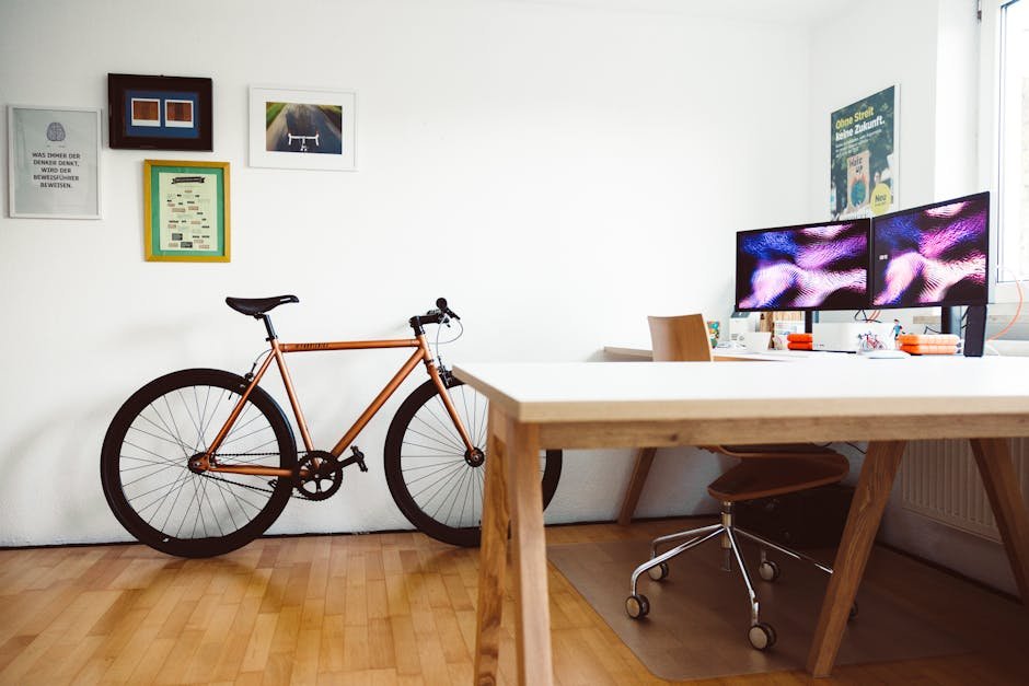 Stylish office setup featuring a bicycle and dual monitors on a wooden desk, ideal for a creative workspace.